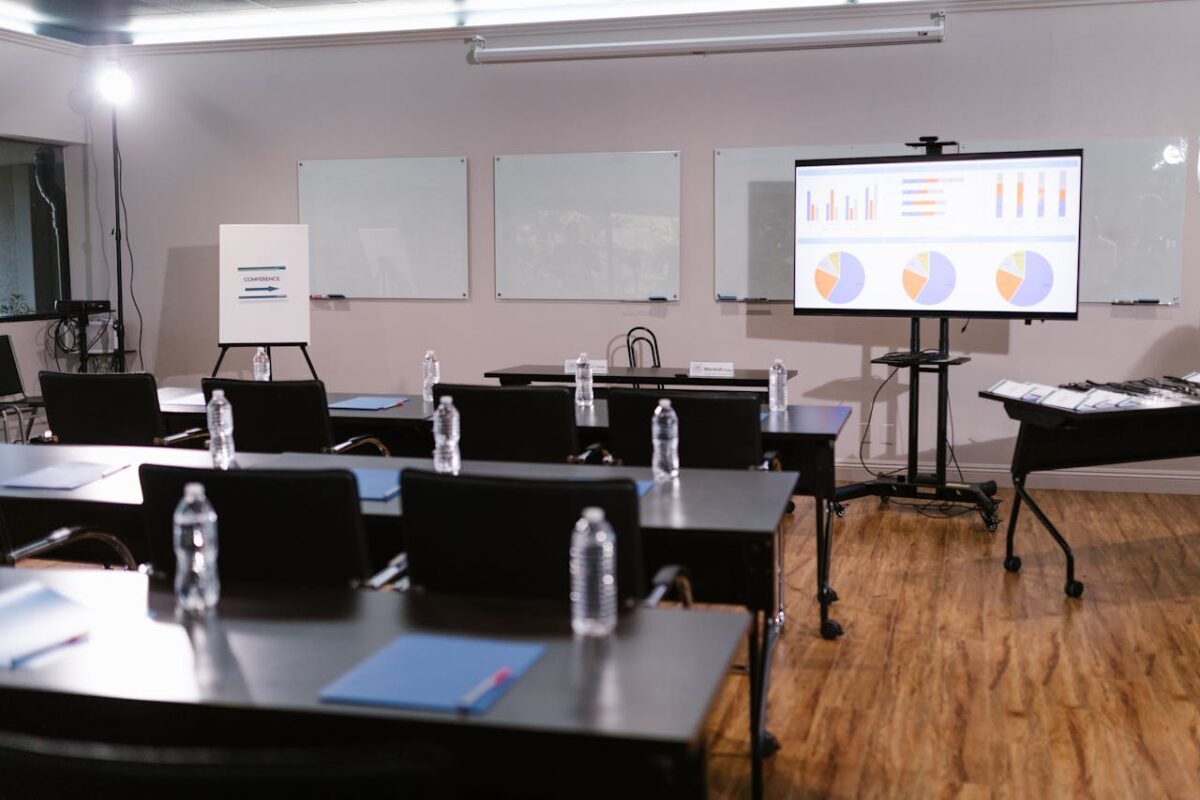 Modern conference room with projector, graphs, chairs, and bottled water setup for presentation.